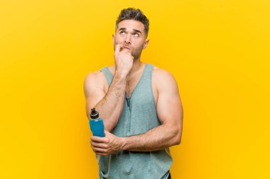 Caucasian man holding an energy drink relaxed thinking about something looking at a copy space.