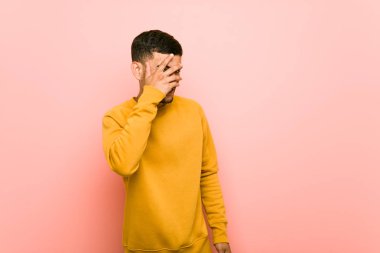 Genç İspanyol adam parmakları ile kameraya göz kırptı, yüz kapsayan utandım.