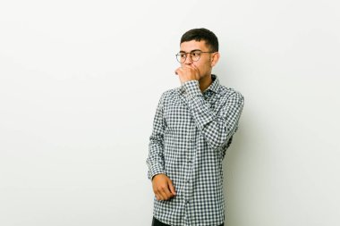 Genç İspanyol adam düşünceli el ile ağız kapsayan bir kopyasını alan arıyor.