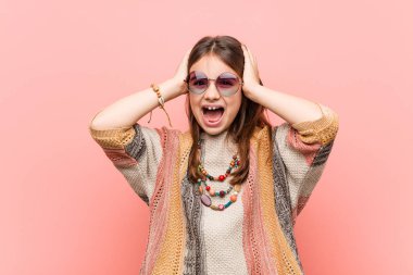 Küçük hippi kız sevinçle baş elleri tutarak gülüyor. Mutluluk kavramı.