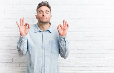 Bir tuğla duvara karşı genç yakışıklı adam zor iş gününden sonra rahatlatır, o yoga yapıyor.