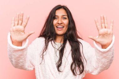 Pijama giyen genç hintli kadın elleri ile on numara gösteren.