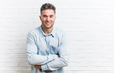 Bir tuğla duvara karşı genç yakışıklı adam gülerek ve eğlenmek.