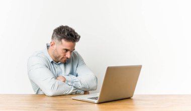 Genç yakışıklı adam alaycı ifade ile kamera bakarak onun laptop ile mutsuz çalışan.