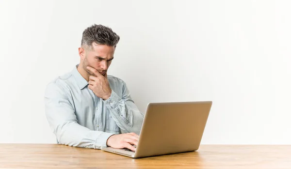 Joven Hombre Guapo Trabajando Con Portátil Mirando Lado Con Expresión —  Fotos de Stock