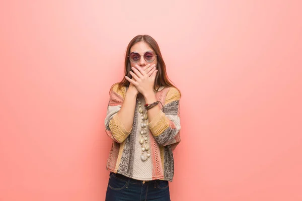 Young hippie woman on pink background surprised and shocked