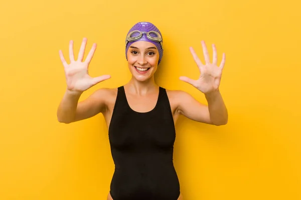 Young swimmer caucasian woman showing number ten with hands.