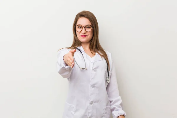 Jonge Dokter Vrouw Tegen Een Witte Muur Stretching Hand Camera — Stockfoto