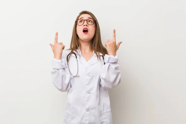 Jonge Dokter Vrouw Tegen Een Witte Muur Wijzend Ondersteboven Met — Stockfoto