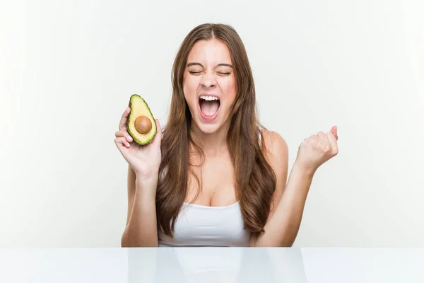 Mujer Caucásica Joven Sosteniendo Aguacate Animando Despreocupado Emocionado Concepto Victoria —  Fotos de Stock