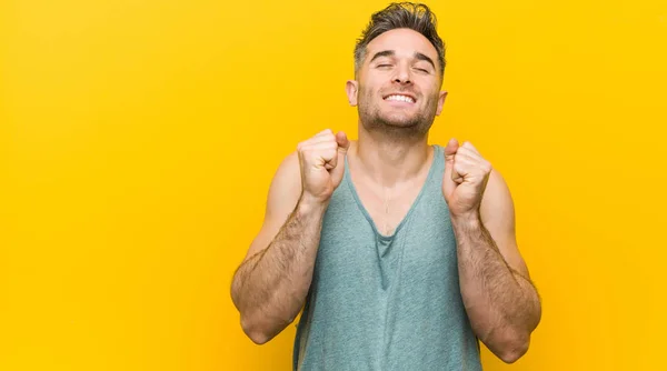 Joven Hombre Fitness Contra Fondo Amarillo Levantando Puño Sintiéndose Feliz —  Fotos de Stock