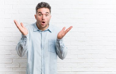 Bir tuğla duvara karşı genç yakışıklı adam şaşırttı ve şok.