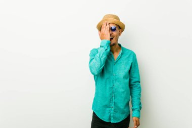 Genç İspanyol adam palmiye ile yüz yarısını kapsayan eğlenceli bir yazlık giysiler giyiyor.