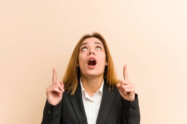 Kafkasyalı genç iş kadını ağzı açık bir şekilde üst tarafı işaret ediyor..