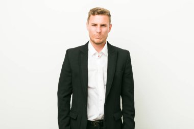 Genç beyaz işadamı yanaklarını üflüyor, yorgun bir ifade yemiş. Yüz ifadesi kavramı.