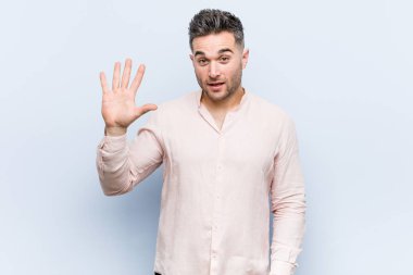 Genç yakışıklı serin adam gülümseyen neşeli parmakları ile beş numara gösteren.