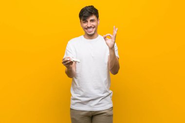 Genç İspanyol adam bir uçak simgesi neşeli ve kendinden emin ok jest gösteren tutan.