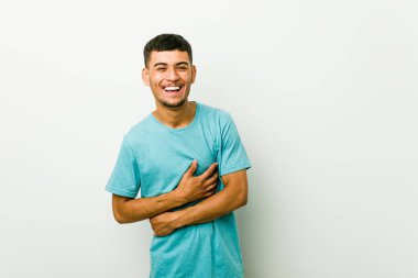 Genç İspanyol adam mutlu güler ve mide ellerini tutarak eğleniyor.