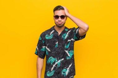 Genç filipinli adam yazlık giysiler giyen yorgun ve çok uykulu baş el tutmak.