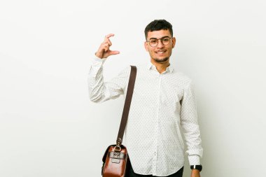 Genç İspanyol rahat iş adamı ön parmakları ile küçük bir şey tutan, gülümseyen ve kendinden emin.