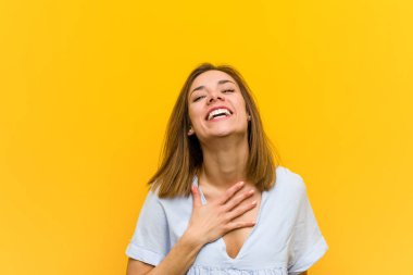 Genç güzel genç kadın yüksek sesle göğüs üzerinde el tutarak gülüyor.