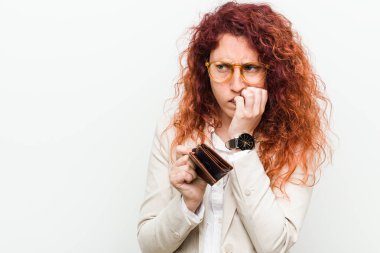 Genç beyaz kızıl saçlı kadın elinde bir cüzdan tutan tırnakları ısıran, sinirli ve çok endişeli.