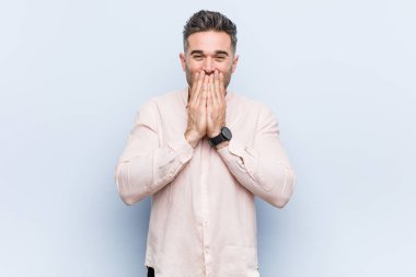 Genç yakışıklı serin adam bir şey hakkında gülüyor, elleriyle ağız kapsayan.