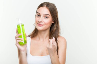 Aloe vera şişesi tutan genç beyaz kadın seni işaret ediyor sanki davet ediyormuş gibi yaklaşAbiliyormuş gibi..