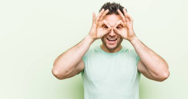 Gözleri üzerinde tamam işareti gösteren yeşil bir arka plan karşı genç yakışıklı adam