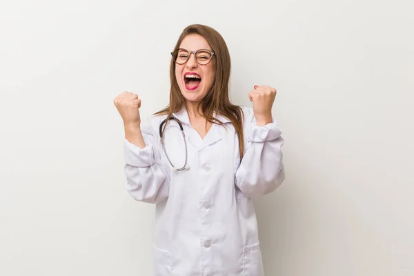 Jonge Dokter Vrouw Tegen Een Witte Muur Juichen Zorgeloos Opgewonden — Stockfoto
