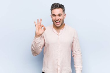 Genç yakışıklı serin adam bir göz kırpıyor ve el ile tamam bir jest tutar.