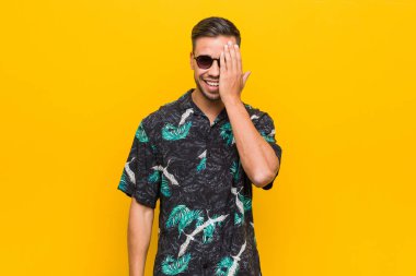 Genç filipinli adam palmiye ile yüz yarısını kapsayan eğlenceli yazlık giysiler giyiyor.