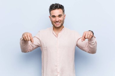 Genç yakışıklı serin adam parmakları ile aşağı işaret, olumlu duygu.