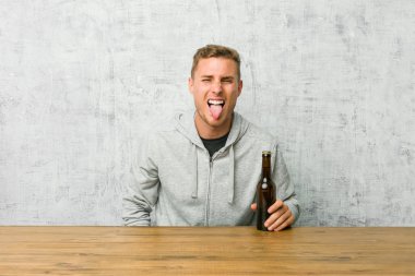 Genç adam bir masada bira içme komik ve dost çakar dil dışarı yapışmasını.