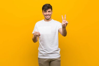 Elinde parmaklarıyla iki numarayı gösteren bir pankart tutan İspanyol genç adam.