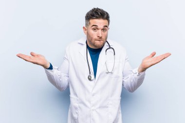 Genç yakışıklı doktor adam karışık ve şüpheli omuzsilke bir kopyasını alanı tutmak için omuzsilkme.