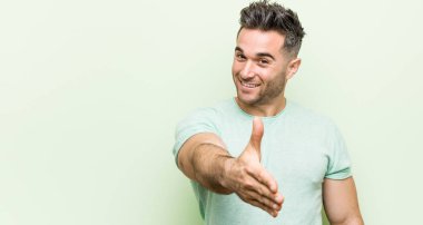 Tebrik jesti kamera da el germe yeşil bir arka plan karşı genç yakışıklı adam.