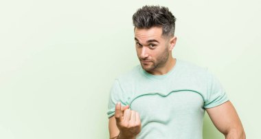 Yeşil bir arka plan aleyhine genç yakışıklı adam daha yakın gelmek davet ediyor gibi parmak ile işaret.