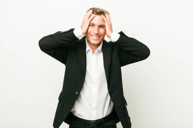 Genç kafkas iş adamı sevinçle başını elleri tutarak gülüyor. Mutluluk kavramı.