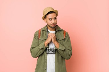 Genç filipinli gezgin adam çene altında ellerini tutar, bir yana mutlu görünüyor.