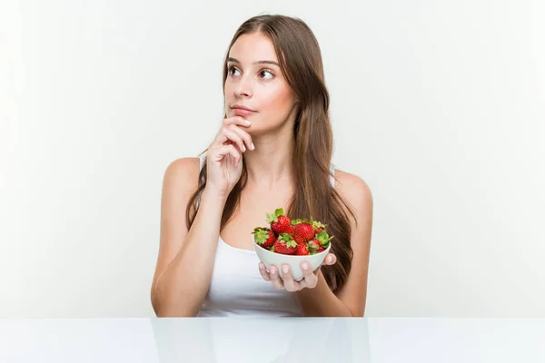 Giovane Donna Caucasica Che Tiene Una Ciotola Fragole Guardando Lateralmente — Foto Stock