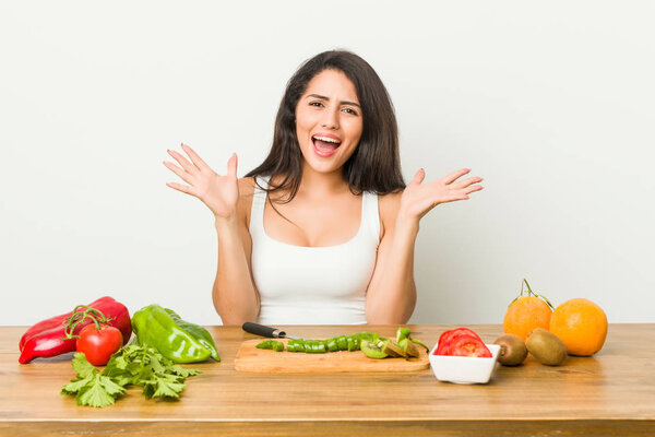 Молодая пышная женщина готовит здоровую пищу празднуя победу или успех, он удивлен и шокирован
.