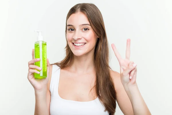 Young Caucasian Woman Holding Aloe Vera Bottle Showing Number Two — Stock Photo, Image