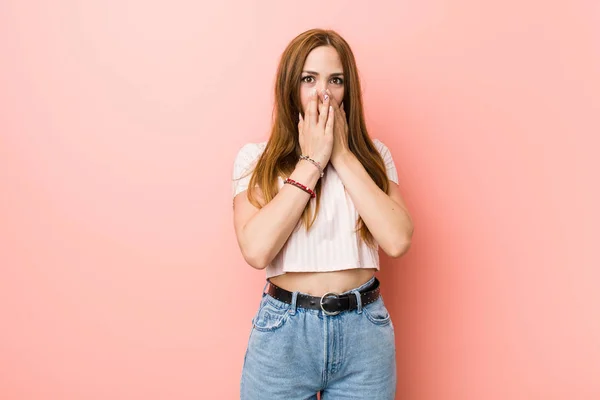 Joven Pelirroja Pelirroja Contra Una Pared Rosa Impactada Cubriendo Boca — Foto de Stock