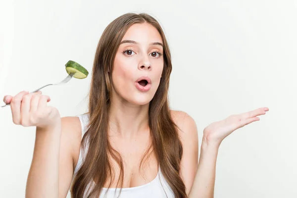 Mujer Joven Caucásica Comiendo Pepino Impresionado Sosteniendo Espacio Copia Palma —  Fotos de Stock