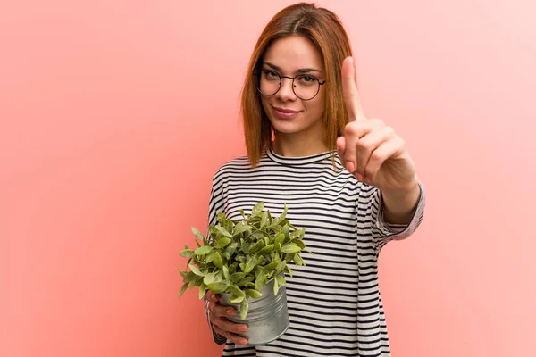 Jonge Vrouw Met Een Plant Die Nummer Één Met Vinger — Stockfoto