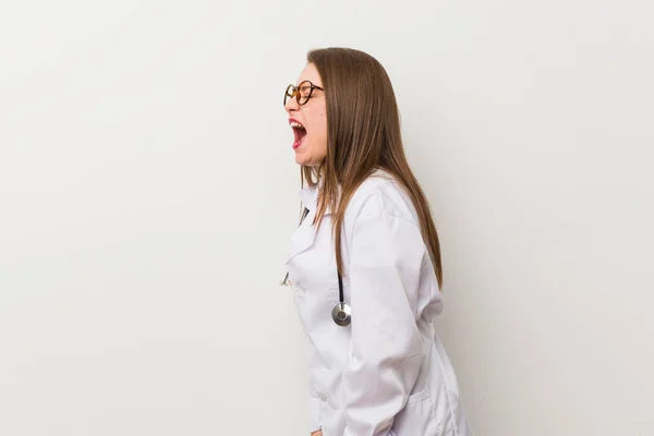 Jonge Dokter Vrouw Tegen Een Witte Muur Schreeuwen Naar Een — Stockfoto