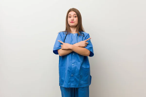 Young Nurse Woman White Wall Points Sideways Trying Choose Two — Stock Photo, Image