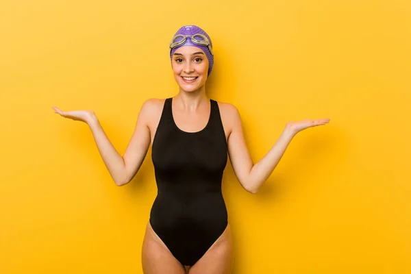 Young swimmer caucasian woman makes scale with arms, feels happy and confident.