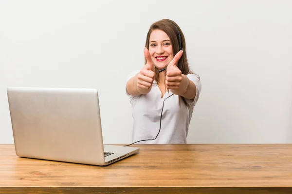 Young telemarketer woman with thumbs ups, cheers about something, support and respect concept.